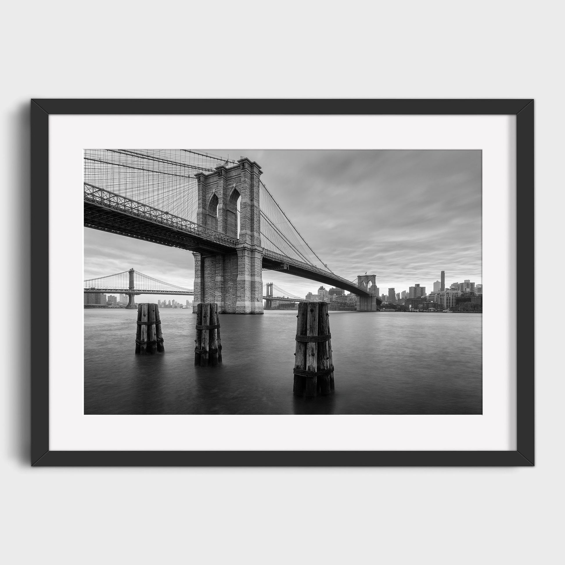 Framed black and white photograph of the Brooklyn Bridge over water with a city skyline in the background. East River Reverie, New York. Beautiful fine art landscape photography wall art for sale. Dermot O'Kane.