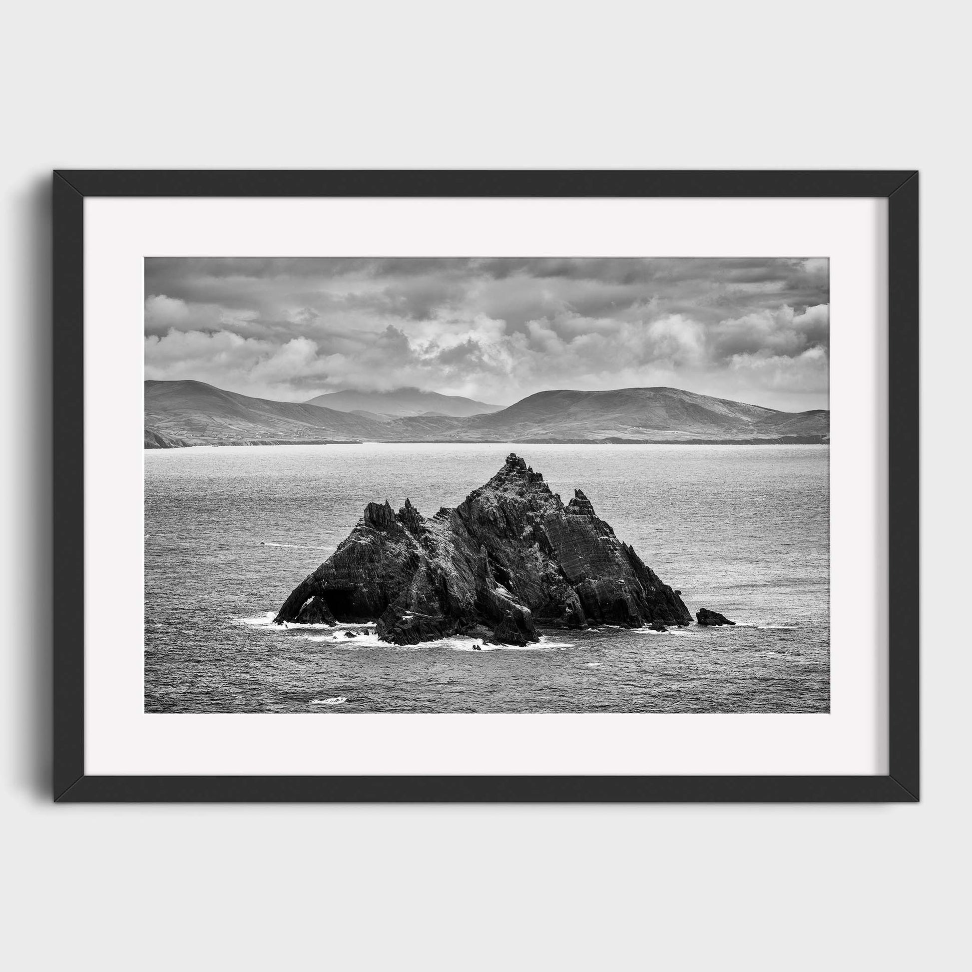 Framed black and white photograph of a rocky island in the ocean with mountains in the background. Little Skellig, Co. Kerry, Ireland, Luke Skywalker, Star Wars Island, Beautiful fine art landscape photography wall art prints for sale. Dermot O'Kane
