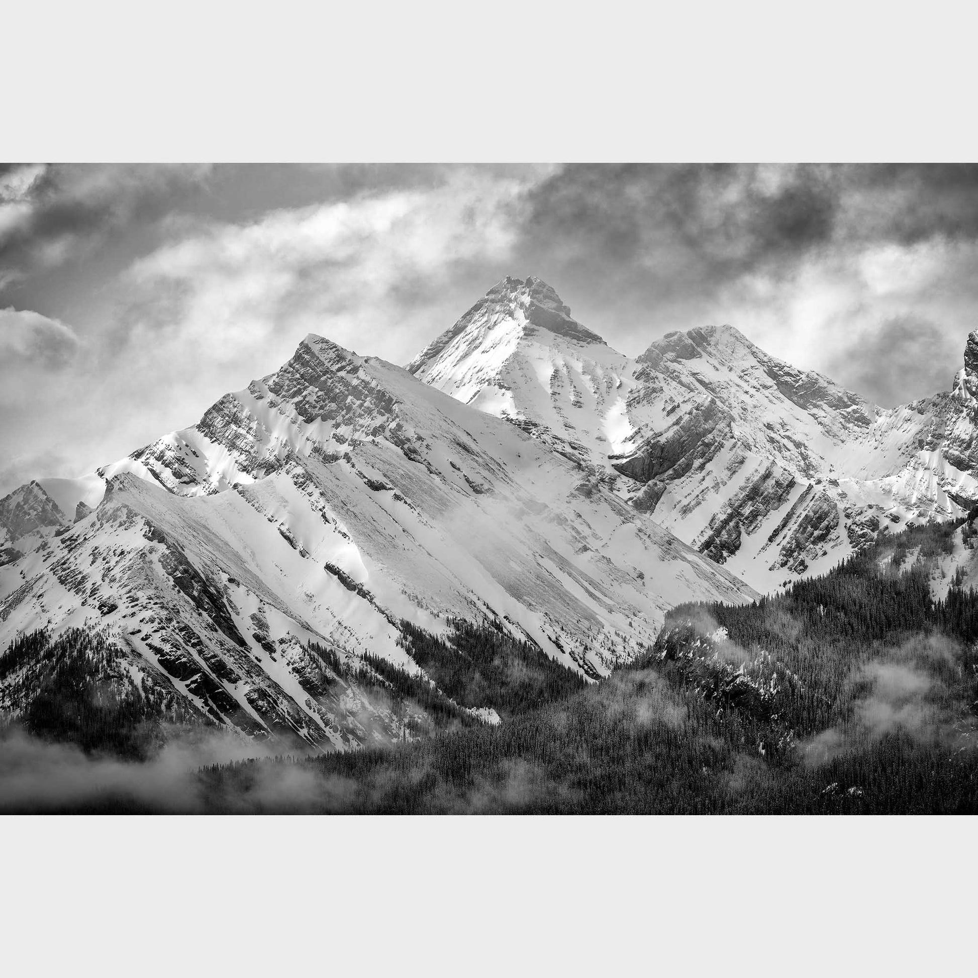 Black and white photograph of snow-capped mountains with clouds in the sky. Misty Mountains, Mount Murray, Kananaskis Country, Alberta, Canada, Rocky Mountains