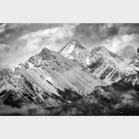 Black and white photograph of snow-capped mountains with clouds in the sky. Misty Mountains, Mount Murray, Kananaskis Country, Alberta, Canada, Rocky Mountains