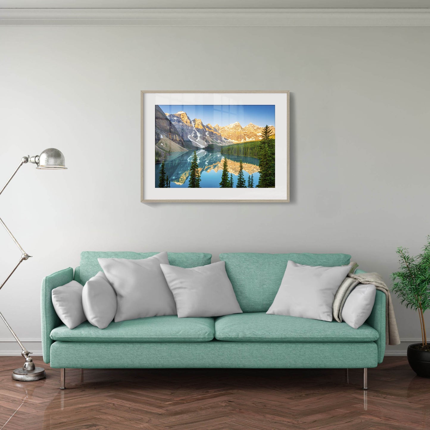Teal sofa with gray pillows in a living room with a framed mountain landscape picture on the wall. Moraine Lake, Banff National Park, Alberta, Canada, Beautiful fine art landscape photography wall art prints for sale. Dermot O'Kane