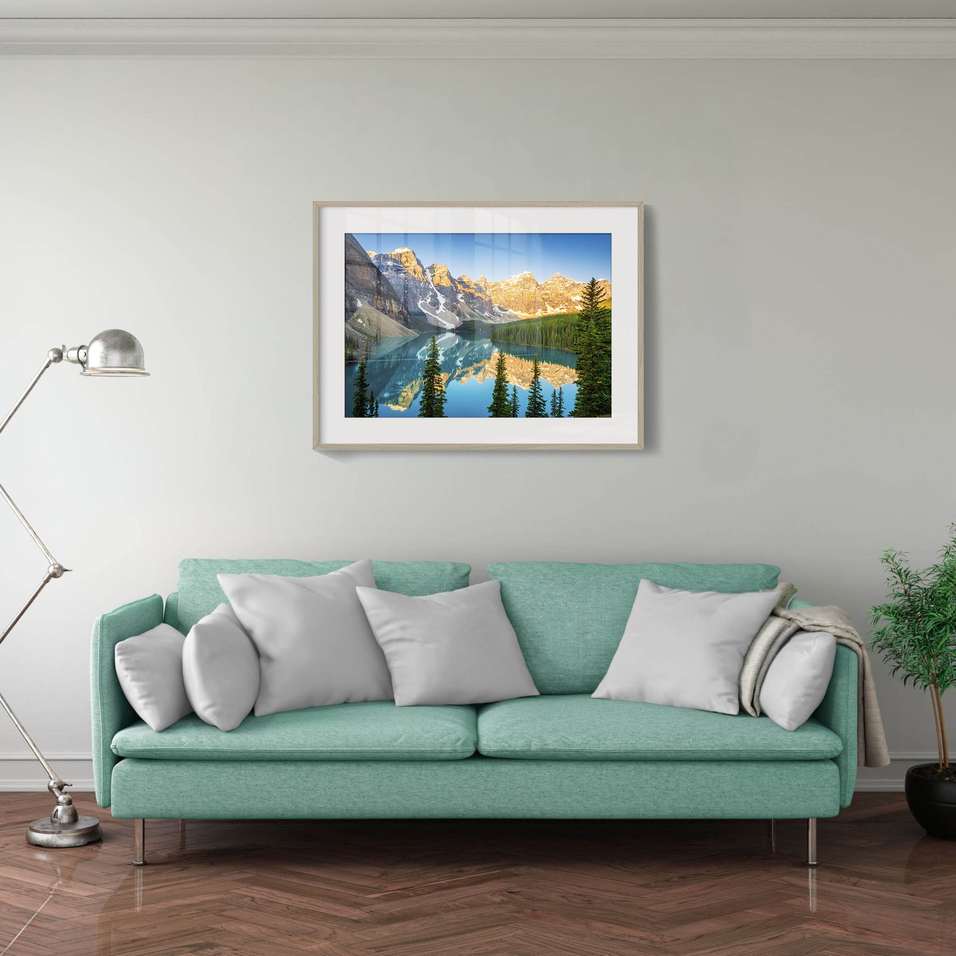 Teal sofa with gray pillows in a living room with a framed mountain landscape picture on the wall. Moraine Lake, Banff National Park, Alberta, Canada, Beautiful fine art landscape photography wall art prints for sale. Dermot O'Kane