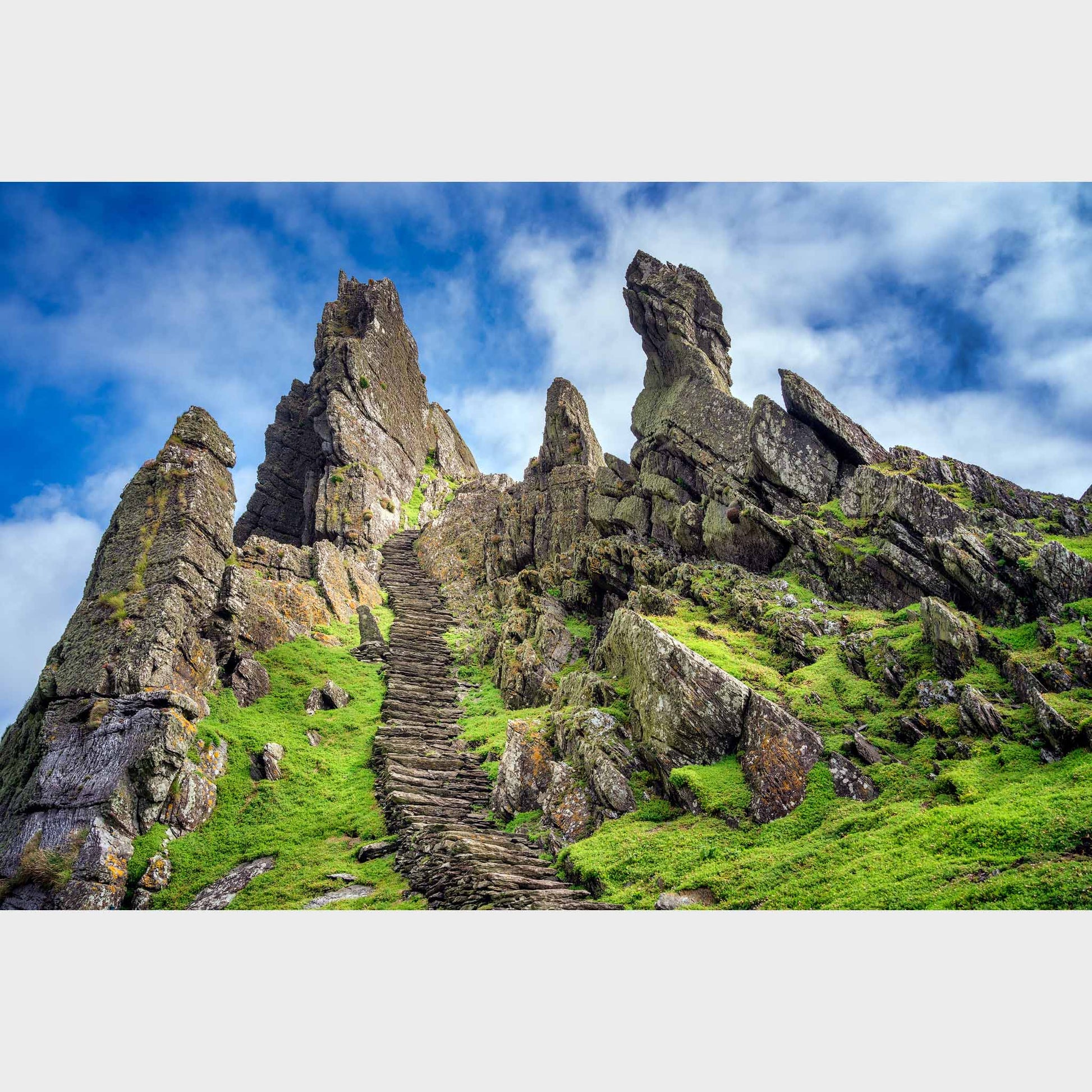 Rocky landscape with a staircase leading up to a craggy peak under a blue sky. Skellig Michael Steps, Co. Kerry, Ireland, Beautiful fine art landscape photography wall art limited edition prints for sale.